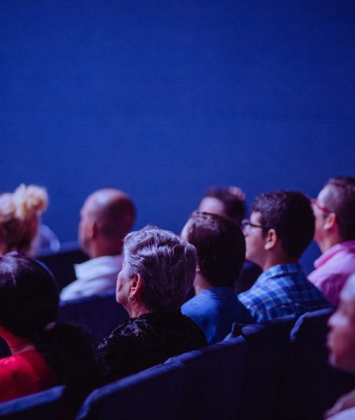 A group of people sitting in an auditorium watching a movie.